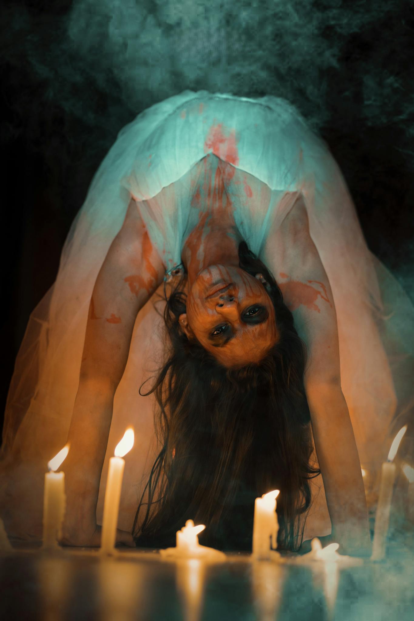 Terrifying horror figure in white dress surrounded by candles, creating an eerie atmosphere.